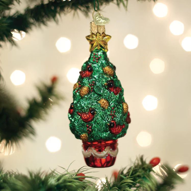 Decorative Christmas tree ornament with red berries and gold accents on a blurred Christmas tree background.