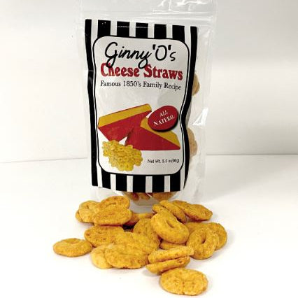 A clear plastic bag with black and white striped design containing Ginny O's Cheese Straws. The bag is placed on a white surface and there are cheese straws spilled out in front of it.