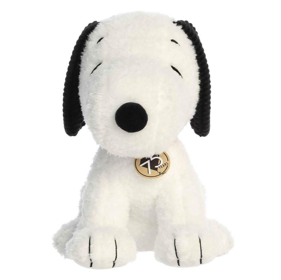 Plush dog toy with black and white fur and a gold tag on a white background