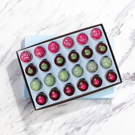 Box of colorful chocolate truffles on a marble surface
