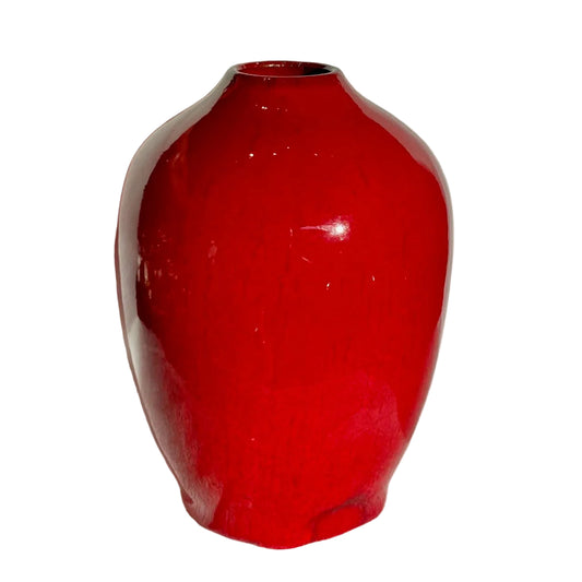 Red ceramic vase on a white textured surface