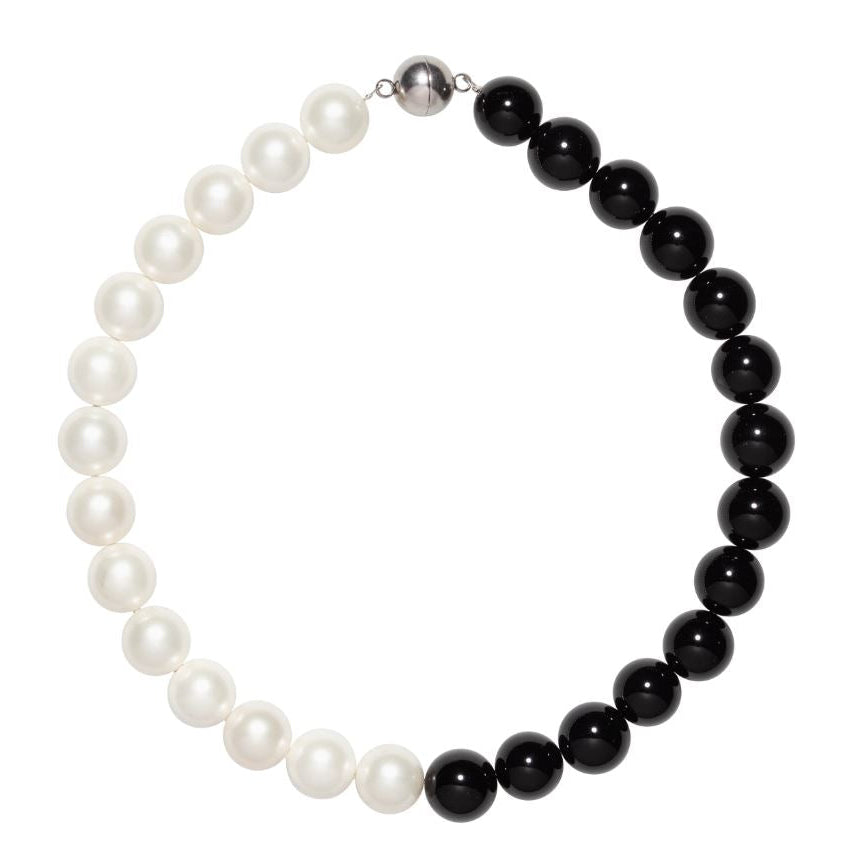 Necklace with alternating white pearls and black beads on a white background