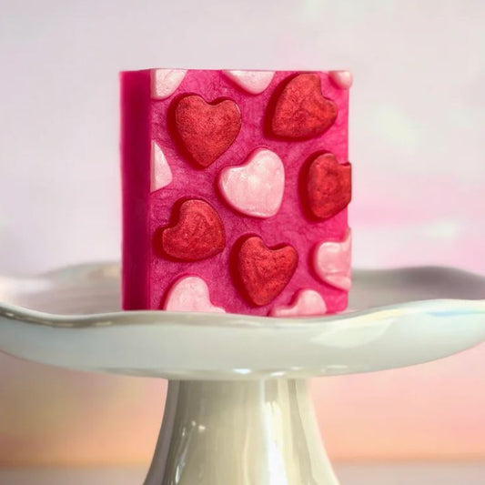 Heart-shaped candy mold on a white stand with a pink and white background