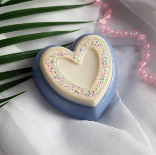 Heart-shaped object with colorful sprinkles on a white fabric background