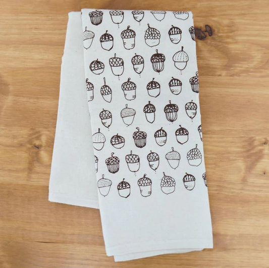 White towel with acorn pattern on a wooden surface