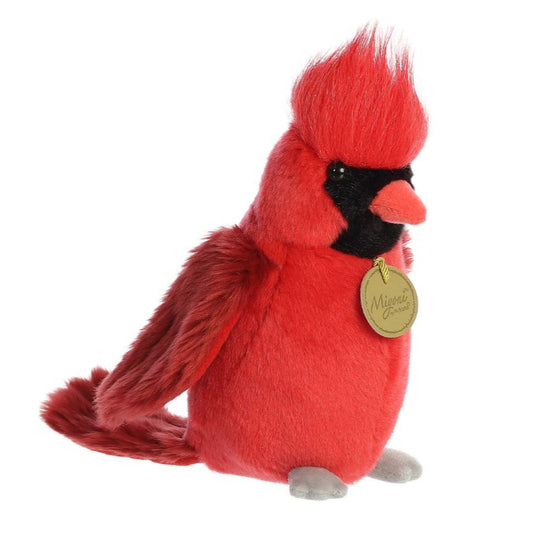 Red plush cardinal bird with a gold tag on a white background