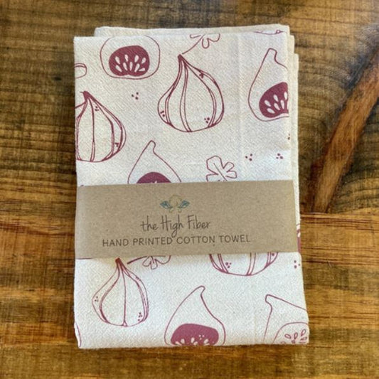 Folded hand-printed cotton towel with fig pattern on a wooden surface, branded 'the High Fiber'.