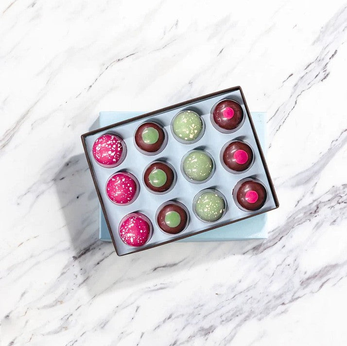 Box of colorful glittery chocolates on a marble surface