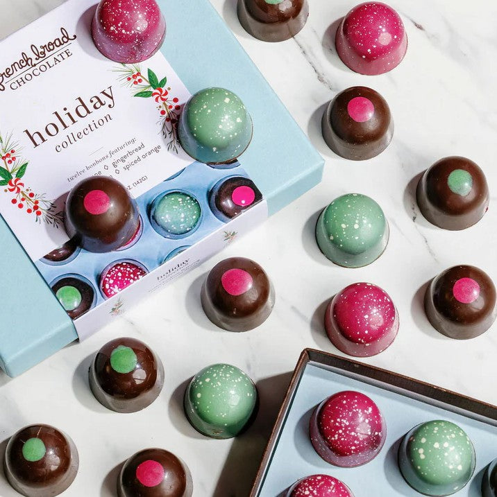 Colorful chocolate truffles in a 'holiday collection' box on a white surface.