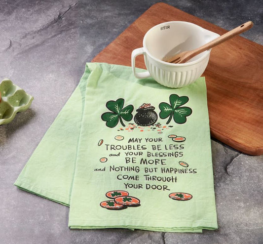 Green towel with shamrock design and text on a kitchen counter with a mug and spoon.