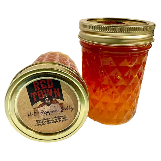 Two jars of Red Town hot pepper jelly with gold lids on a white background