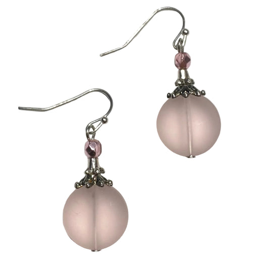 Pair of pink spherical earrings with silver hooks on a white background
