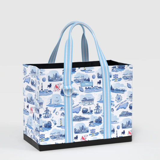 A tote bag with a white background and a blue nautical-themed illustration pattern, featuring light blue and white striped handles and black trim at the base.